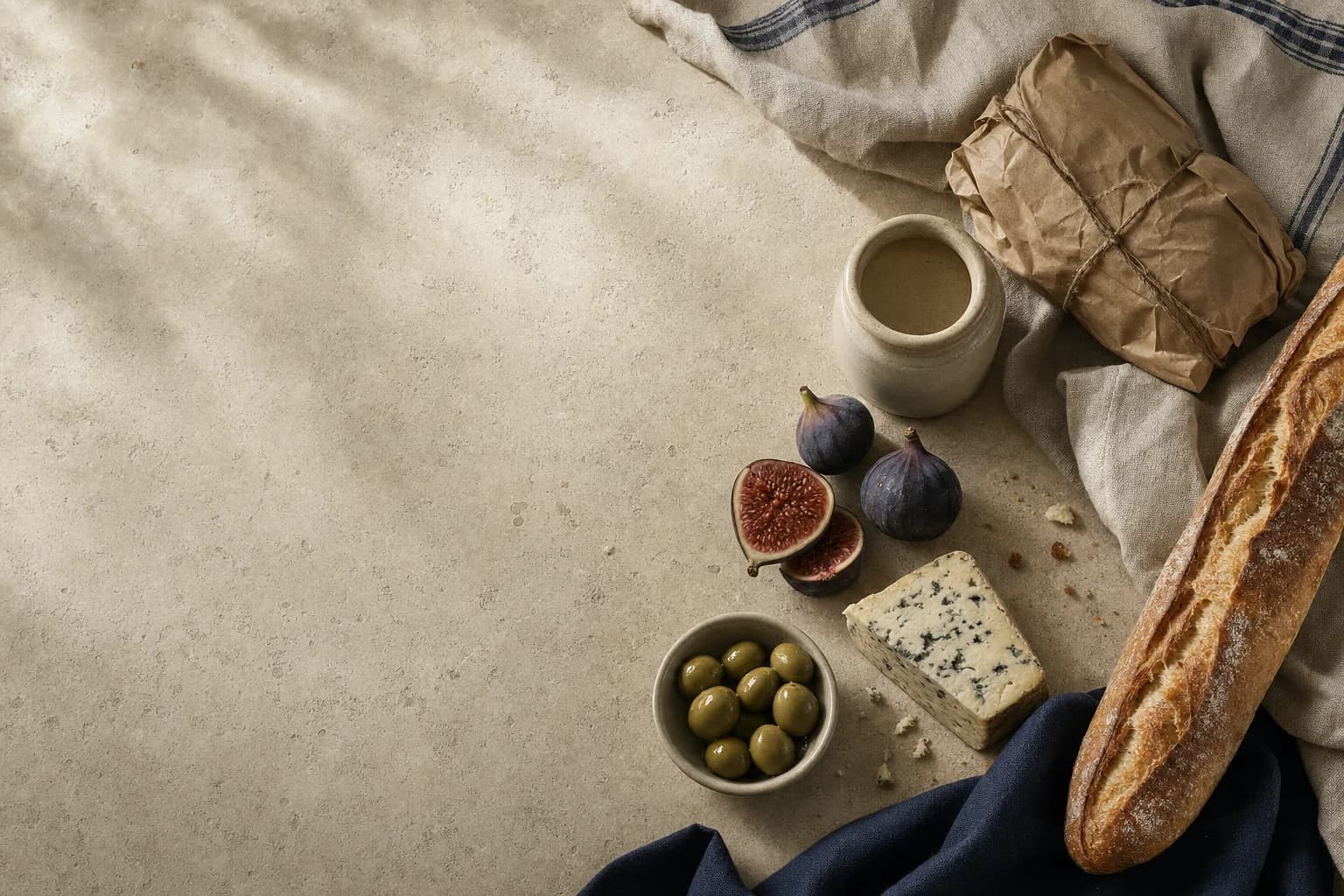 A French-inspired table with bread, figs, olives, cheese, and a linen-wrapped parcel